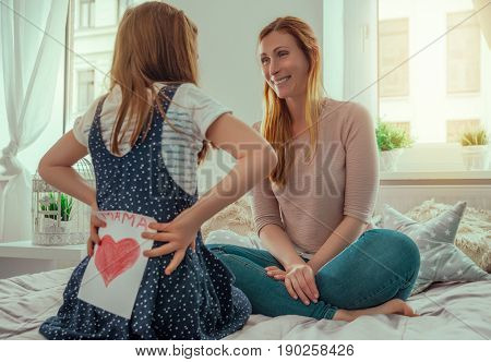girl surprising parents with greeting card at home