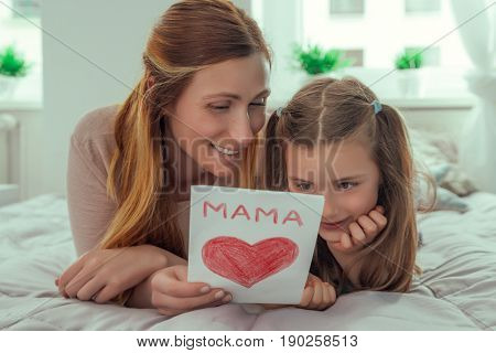 girl surprising parents with greeting card at home