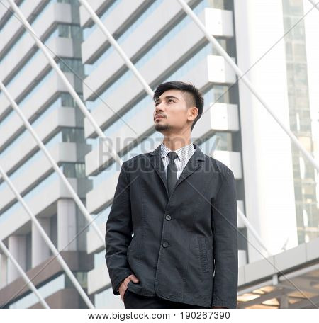 Lifestyle of handsome young Asian businessman standing in modern city against the background of urban landscape.
