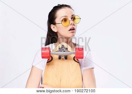 A woman with a skateboard in her hands. Woman in the studio with skateboard.