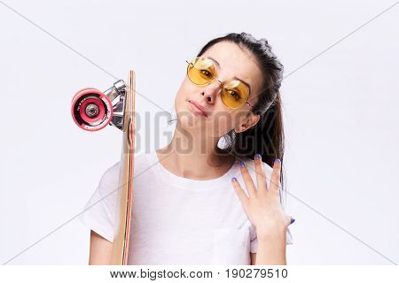 A woman with a skateboard in her hands. Woman in the studio with skateboard.