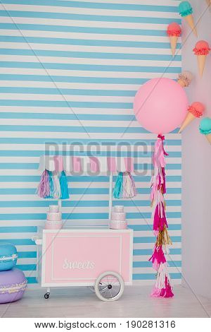 Children's zone with sweets: lollipops, ice cream, macarons, balloon and candy bar. Children room with blue stripe background.