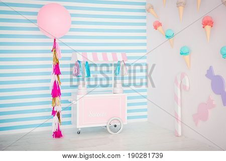 Children's zone with sweets: lollipops, ice cream, macarons, balloon and candy bar. Children room with blue stripe background.