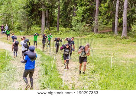 Stockholm Sweden - June 03 2017: View from above of a group of runners carry heavy sacks up a grass hill course to complete the annual event Toughest Stockholm.