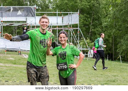 Stockholm Sweden - June 03 2017: Close up front view man and woman wet and dirty after completing a mud obstacle at the annual event Toughest Stockholm. A few people in the background.