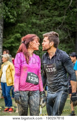 Stockholm Sweden - June 03 2017: Close up front view man and woman wet and dirty after completing a mud obstacle at the annual event Toughest Stockholm. A few people in the background.