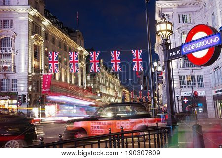 London, England, United Kingdom: 16 June 2017 - Popular tourist Picadilly circus with flags union jack in night lights illumination