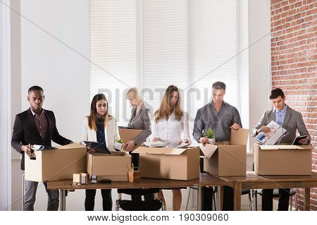 Group Of Diverse Businesspeople Packing Their Belongings In Cardboard Box At Office