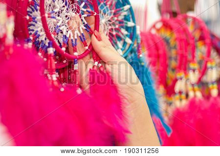 OTAVALO, ECUADOR - MAY 17, 2017: Close up of a woman holding a pink catchdreamer in her hand, in colorful market background.