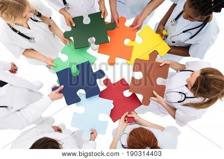 High Angle View Of Medical Team Solving Jigsaw Puzzle