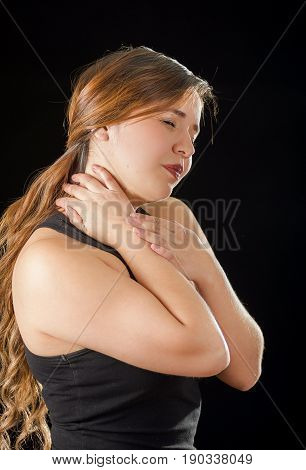 Beautiful young lady Suffer crick after workout in a black background.