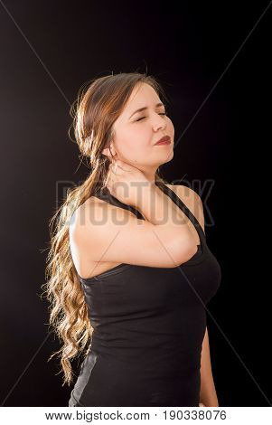 Beautiful young lady Suffer crick after workout in a black background.