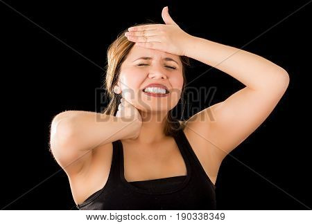 Close up of a beautiful young lady Suffer crick after workout with a hand in her forehead, in a black background.