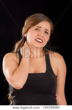 Beautiful young lady Suffer crick after workout in a black background.