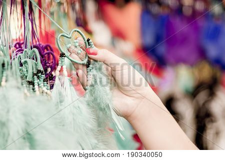 OTAVALO, ECUADOR - MAY 17, 2017: Close up of a woman holding a catchdreamer in her hand, in colorful market background.