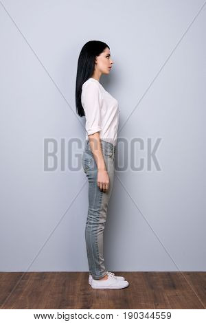 Full Size Profile View Of Brunette Girl In Casual Outfit And White Shoes On Pure Grey Background. Mo