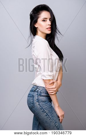 Cute Flirty Brunette In Casual Outfit Is Looking Flirty And Stands In A Pose On A Pure Grey Backgrou