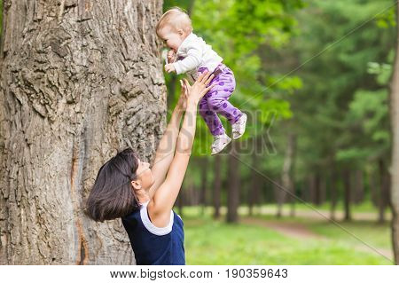 happy family - Mother throws up baby, playing outdoors.