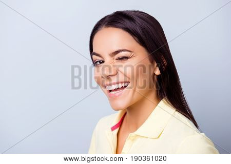 Successful smiling latino  girl is winking on light blue background. She has a beaming smile!