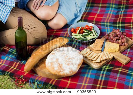 High angle view of wine bottle and food by couple on picnic blanket