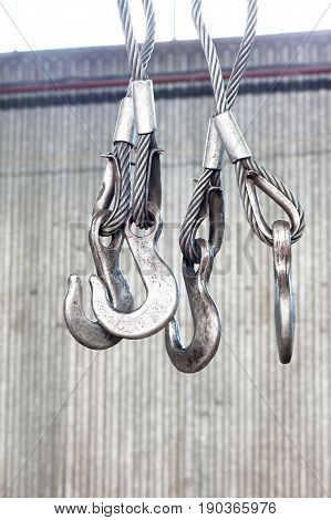 Iron industrial hooks on a ropes in warehouse. Metal engineering. Indoors close-up.
