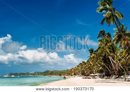 Tropical beach with palm trees pilippine boats sunbeds blue sky turquoise water and white sand. Paradise. Philippines Boracay. Wide angle horizontal
