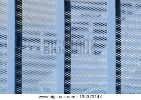 blue Background sheet of metal covered with lines of circular holes