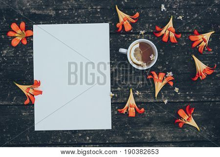 Cup of tea with yellow and white flowers on old board.