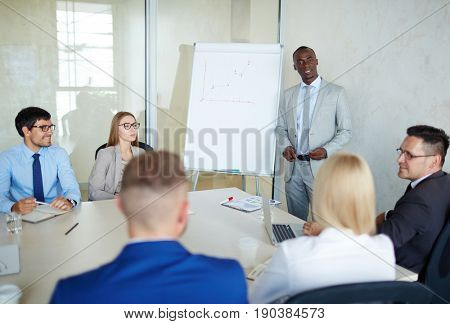 Multi-ethnic team of talented managers discussing growth strategy of their company while sitting in modern board room