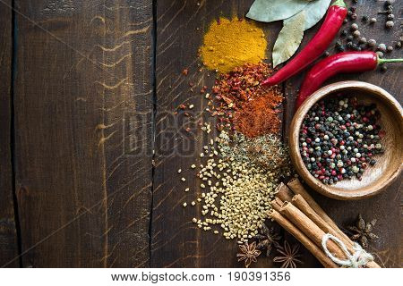 Pepper In Bowl With Scattered Herbs And Spices, Laurel Leaves, Chili Peppers On Wooden Tabletop