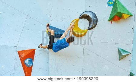 man climber climbs a bouldering problem on climbing gym. man mekes hard wide move. Climbing competition