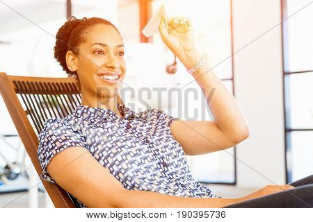 Young woman in office holding paper plane