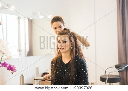 working day inside the beauty salon. Hairdresser makes hair styling.