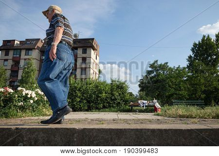 BELGRADE SERBIA - JUNE 03 2017: Old man walking near an senior woman sleeping on a bench in the district of Doni Dorcol belgrade