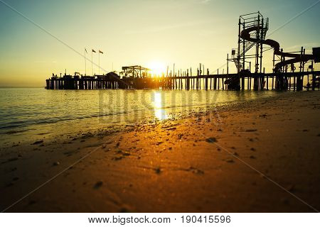 Golden dawn over the beach with water playground on jetty .Rawa island Malaysia . Selected focus on center .
