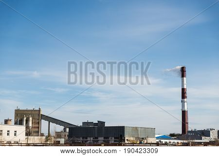 factory chimney releasing white smoke into the blue sky