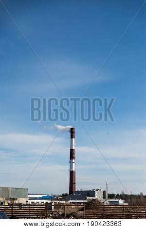 factory chimney releasing white smoke into the blue sky