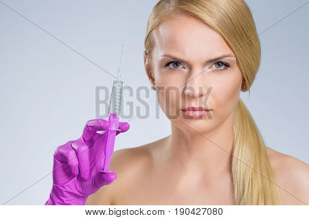 Serious Pretty Woman Holding Syringe In Hand In Glove