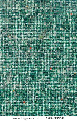 A pattern of green tiles with red spots