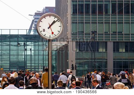 London UK - May 10 2017 - A public clock in Reuters Plaza Canary Wharf packed with people walking through