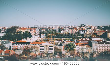 Aerial panoramic shooting from observation point of central Lisbon district on sunny day: multiple ancient houses plants construction cranes clear sky and reflections with aberrations in the bottom