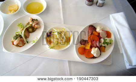 FRANKFURT, GERMANY - SEPTEMBER 28, 2014: First Class Dining onboard an Boeing 747 upper deck from Lufthansa, white wine, water and appetizer.