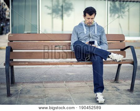 A Man Sitting On A Wooden Bench Relaxed And Testing Your Phone