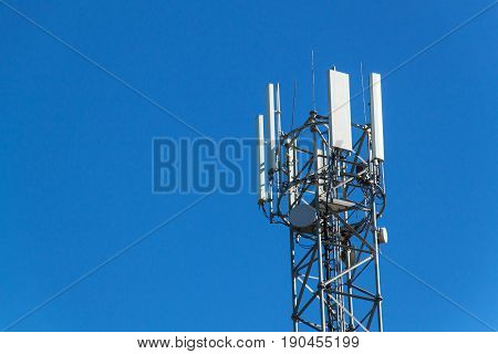 Technology on the top of the telecommunication GSM. Masts for mobile phone signal. Tower with antennas of cellular communication on the background of blue sky.