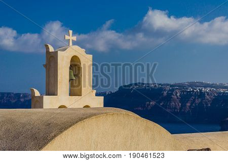 The cross that crowns the belfry of FIRA in Santorini - Greece