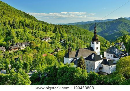 Spring in Slovakia. Old mining village. Historic church in Spania dolina. Springtime colored trees at sunset.