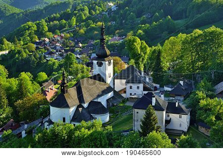 Spring in Slovakia. Old mining village. Historic church in Spania dolina. Springtime colored trees at sunset.