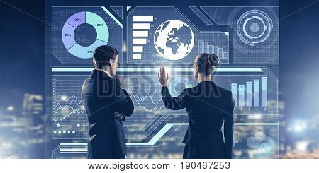Two business people standing with back and working together with virtual screen