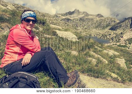 Female trekker resting on mountain meadow. Treking 5 Laghi above Madonna di Campiglio, Brenta in Italy.