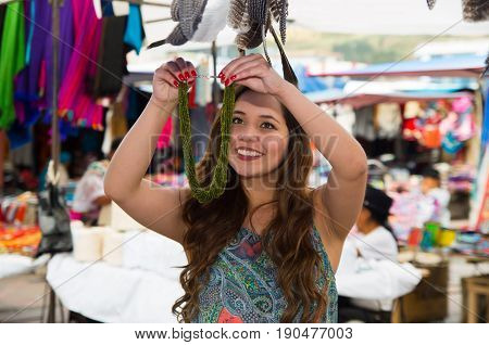 Beautiful woman holding an andean traditional clothing and handicrafts necklace art, colorful necklace background.
